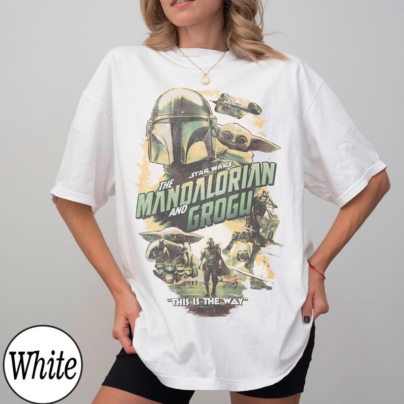 K&ouml;nnte beinhalten: Wei&szlig;es T-Shirt mit einem Grafikdesign aus der Star Wars-Serie "The Mandalorian and Grogu". Das Design zeigt den Helm des Mandalorianers, Grogu und den Satz "This is the Way".