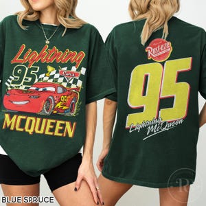 May include: Blue spruce t-shirt featuring Lightning McQueen from the Cars movie. The front graphic shows McQueen with the number 95, the text "Lightning" and "McQueen". The back displays a large number 95 and the text "Lightning McQueen".
