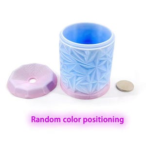 May include: A cylindrical container with a geometric pattern in light blue and pink, with a matching lid and a small silver disc. The text "Random color positioning" is displayed in purple.