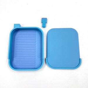 May include: A light blue craft tray set, including a tray with a ridged interior, a lid, and a small, rectangular tool. The tray and lid are made of plastic. The set is designed for crafting and organizing small items.