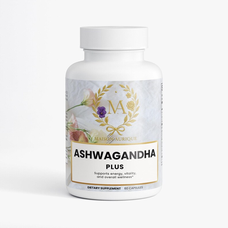 May include: White supplement bottle with a white lid. The label features the text "ASHWAGANDHA PLUS" and "MAISON AURIQUE". The label also includes a gold wreath design with the letter "M" inside. The bottle contains 60 capsules.