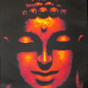 May include: A close-up of a red and orange Buddha face with a traditional headdress. The face is serene and peaceful, with closed eyes and a gentle smile.