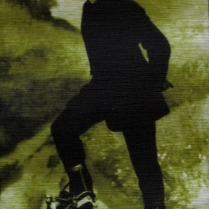 May include: A black and white vintage photograph of a person wearing a cap and riding a bicycle with a single front wheel and two rear wheels.
