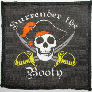 May include: Black fabric patch with a white skull and crossbones, a pirate hat, and the text "Surrender the Booty".