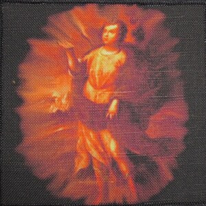 May include: A black woven patch with a colorful image of a person in a flowing garment, surrounded by a swirling orange and red background.