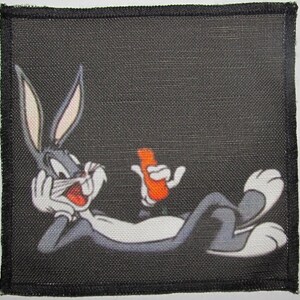 Könnte beinhalten: Ein schwarz-weißes Cartoon-Kaninchen mit einer Karotte in der Hand, das auf einem schwarzen Hintergrund liegt.