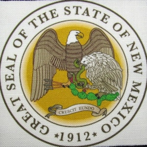 Może przedstawiać: Wielka Pieczęć Stanu Nowy Meksyk, przedstawiająca orła bielika z rozpostartymi skrzydłami, trzymającego węża w szponach. Orzeł siedzi na kaktusach z zielonymi liśćmi. Pieczęć jest otoczona okręgiem z tekstem "Great Seal of the State of New Mexico" i "1912" w brązowych literach. Tekst "Crescit Eundo" znajduje się na zwiniętym zwoju pod orłem.