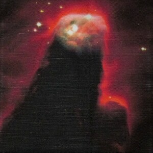 Puede incluir: Un primer plano de una nebulosa oscura y texturizada con un brillo rojo intenso en la esquina superior derecha. La nebulosa está rodeada de un campo de estrellas.