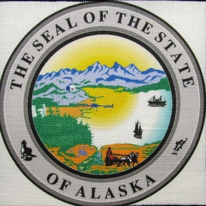 Könnte beinhalten: Das offizielle Siegel des Bundesstaates Alaska zeigt eine Bergkette, ein Gewässer, ein Schiff und einen Mann in einem von Hunden gezogenen Schlitten. Das Siegel ist von den Worten "The Seal of the State of Alaska" umgeben.