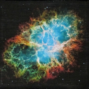 Puede incluir: Imagen cuadrada de una colorida nebulosa sobre un fondo negro. La nebulosa es principalmente azul en el centro, con tonos naranja, verde y rojo irradiando hacia afuera. Pequeñas estrellas blancas están dispersas en los bordes.