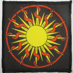 May include: A black fabric patch with a red and yellow sun design. The sun has a yellow center and red rays that curve outward.