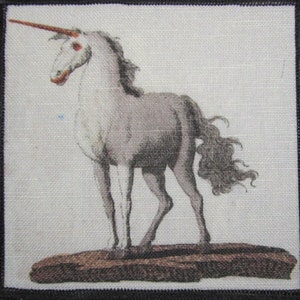 Puede incluir: Un unicornio blanco con un cuerno largo y en espiral se encuentra de pie sobre una roca marrón. El unicornio tiene una larga melena y cola que fluyen. El fondo es gris claro.