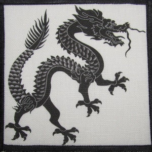 May include: Black and white embroidered patch featuring a stylized dragon with a long tail and sharp claws.