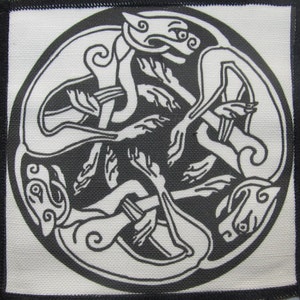 Peut inclure: Patch brodé noir et blanc représentant un motif circulaire de deux chiens entrelacés dans un motif de nœud celtique.