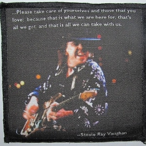 Könnte beinhalten: Quadratischer schwarzer Aufnäher mit einem Bild von Stevie Ray Vaughan, der Gitarre spielt. Der Aufnäher enthält den Text: "Please take care of yourselves and those that you love..." und "Stevie Ray Vaughan" vor dunklem Hintergrund.