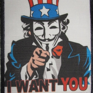 Puede incluir: Un parche blanco con borde negro presenta una imagen de dibujos animados del Tío Sam con un sombrero rojo, blanco y azul y una máscara negra. El texto "I WANT YOU TO OCCUPY YOUR COUNTRY" está impreso en negro debajo de la imagen.