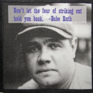 May include: Black and white photo of baseball player Babe Ruth wearing a baseball cap. The quote "Don't let the fear of striking out hold you back. -Babe Ruth" is printed above his head.