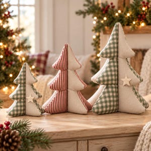 May include: Three fabric Christmas tree ornaments in varying sizes. The smallest and largest trees feature green and white gingham fabric with a small wooden star. The middle tree features red and white striped fabric.