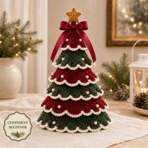 May include: A tiered crochet Christmas tree featuring alternating dark green and deep red layers with scalloped white edges. The tree is adorned with small white pearl beads, topped with a yellow crocheted star, and finished with a dark red satin ribbon bow.