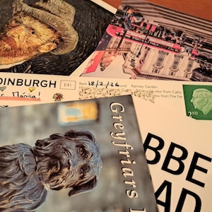 May include: A collection of postcards featuring images of Edinburgh, Scotland, and a portrait. One postcard has the text "EDINBURGH" and a handwritten message. Another shows a statue of a dog. A green stamp is visible.
