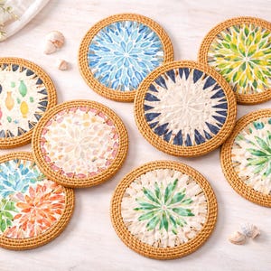 Könnte beinhalten: Eine Sammlung von acht runden Untersetzern mit gewebten Rattanrändern. Jeder Untersetzer hat ein einzigartiges, farbenfrohes Design in der Mitte, einschließlich floraler und geometrischer Muster. Die Untersetzer haben einen Durchmesser von etwa 10 cm.