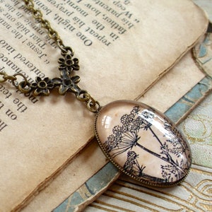 May include: A bronze necklace with a delicate floral design and a pendant featuring a vintage botanical illustration of Queen Anne's Lace on a cream background.