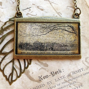 Puede incluir: Un collar de bronce con un colgante en forma de hoja y un dije rectangular con una ilustración vintage de un árbol con la cita "BUT AT EVERY GUST THE DEAD LEAVES FALL".