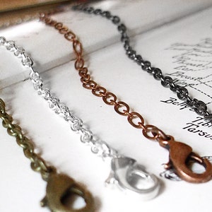 May include: Three different chain styles with lobster clasps. The chains are silver, copper, and bronze.