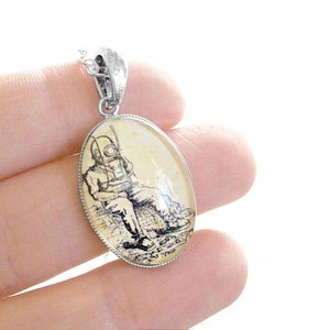 Op de afbeelding: Een zilveren ovale hangerketting met een vintage illustratie van een duiker in een duikpak. De illustratie is gedrukt op een cr&egrave;mekleurige achtergrond.
