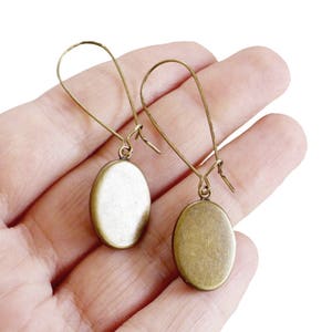 May include: A pair of oval-shaped bronze earrings with a simple wire design.