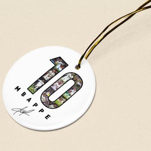 A white circular tag with the number "10" and the text "MBAPE" printed on it, along with a signature.