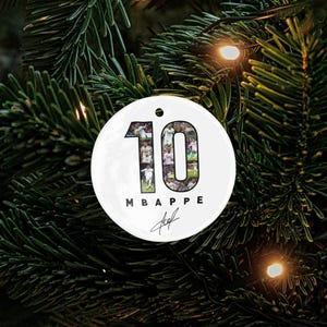 A white ornament with the number 10 and the text "MBAPPÉ" is hanging on a Christmas tree.