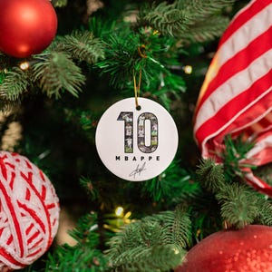 A Christmas tree decorated with ornaments, including a large red ornament, a white ornament with the number 10, and other ornaments in red and white.