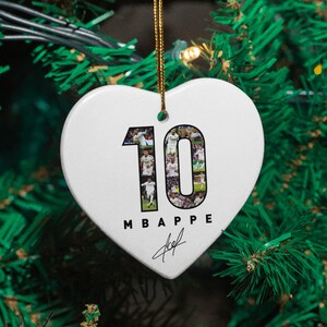A heart-shaped ornament with the number 10 and the text "MBAPE" hanging on a Christmas tree.