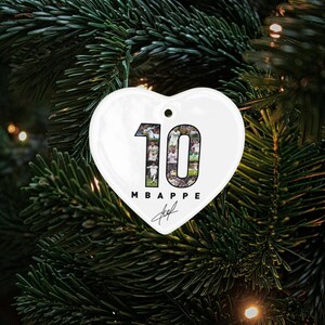 A heart-shaped ornament with the number 10 and the text "MBAPPÉ" is displayed on a Christmas tree.