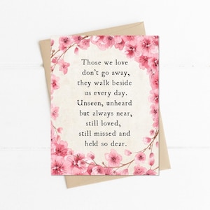 May include: A sympathy card with a floral design and the text "Those we love don't go away, they walk beside us every day." The card features a beige background with pink flowers and is accompanied by a brown envelope.