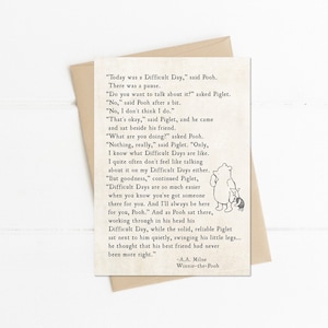 May include: A greeting card with a quote from Winnie-the-Pooh, featuring Pooh and Piglet. The text is in a classic font on an off-white background, with a brown envelope. The quote is about friendship and difficult days.