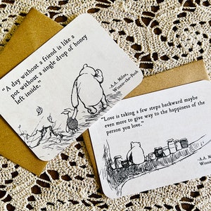 May include: Two Winnie-the-Pooh inspired cards with black and white illustrations and quotes. The first card says "A day without a friend is like a pot without a single drop of honey left inside." The second card says "Love is taking a few steps backward maybe even more to give way to the happiness of the person you love."