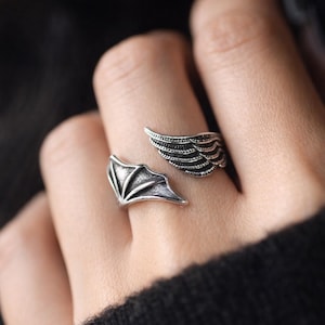 Puede incluir: Anillo plateado con diseño de alas. Una ala envuelve el dedo, la otra se sitúa en la parte superior. El anillo tiene un aspecto detallado y texturizado. Fabricado en metal plateado.
