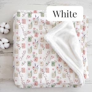 May include: A white fleece blanket featuring a repeating pattern of mahjong tiles, pink flowers, and lavender sprigs. The name Charlotte is printed in a cursive script throughout the design. The blanket has a solid white plush underside.