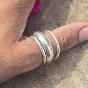 May include: A set of three silver rings worn on a finger, featuring one wide, smooth, domed band flanked by two thinner, rounded bands. The text BalajisilverartIN is overlaid across the centre of the rings in a clear, sans-serif font.