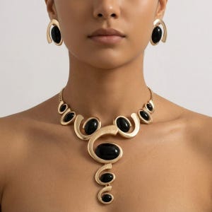 May include: A gold-toned jewelry set featuring a necklace and matching earrings. The necklace has a series of black oval stones set within swirling gold metal designs. The earrings have a similar design, with a single black stone in a gold frame. The jewelry is worn on a person.