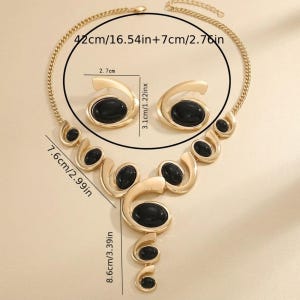 Puede incluir: Juego de collar y pendientes dorados con detalles ovalados negros. El collar mide 42 cm + 7 cm, los pendientes 3,1 cm de alto. El conjunto tiene un dise&ntilde;o &uacute;nico y fluido, ideal para ocasiones especiales.