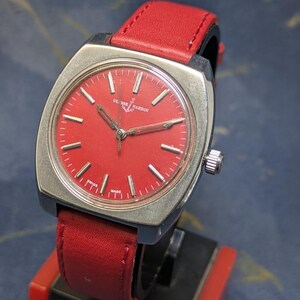 May include: A vintage Ulysse Nardin watch with a square silver case and a vibrant red dial. The watch features silver hands and markers, and a red leather strap. The watch is marked "Swiss Made".