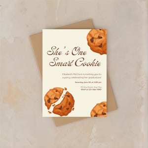以下が含まれることがあります： 「She's One Smart Cookie」のテキストが入った卒業パーティーの招待状。チョコレートチップクッキーのイラストが特徴で、パーティーの詳細が含まれています。カードはベージュ色の背景にあります。