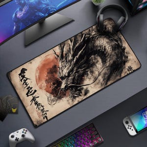 May include: A rectangular mouse mat with a black and white dragon illustration set against a red sun, with Japanese calligraphy. The mat is on a grey surface, surrounded by gaming accessories.