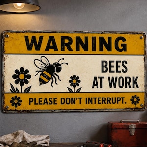 May include: A rectangular metal sign with a yellow and white background featuring a black bee illustration and the text WARNING BEES AT WORK PLEASE DON'T INTERRUPT. The sign has a distressed finish with visible rust along the edges and four holes.