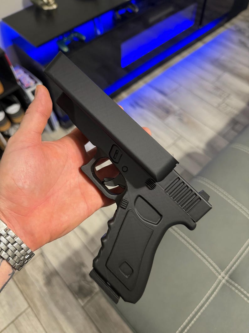 May include: A matte black toy pistol featuring a solid, blocky slide design, a textured grip, a trigger guard, and a trigger. The object has a simplified, non-functional appearance with clean lines and a uniform dark finish throughout the frame.