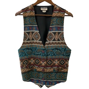 May include: A vintage waistcoat with a colourful tapestry pattern. The waistcoat features a V-neck, button closure, and a black lining. The pattern includes paisley, geometric shapes, and a mix of teal, brown, and burgundy colours. The waistcoat is hanging on a wooden hanger.