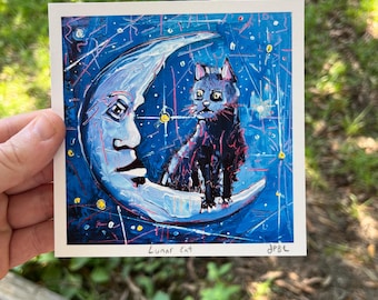 Puede incluir: Un gato negro se sienta en una luna creciente con una cara humana. La luna y el gato están pintados sobre un fondo azul con estrellas blancas y amarillas. El texto "Lunar Cat" está escrito debajo de la imagen.